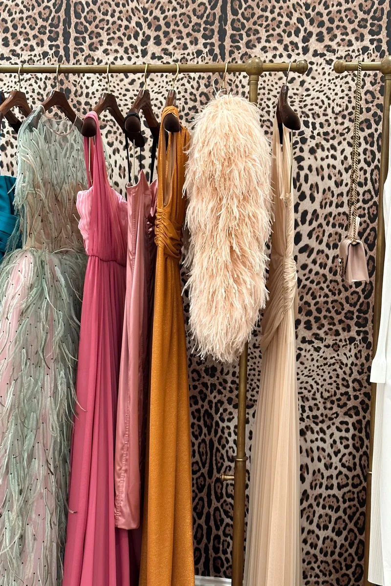 Vestidos largos de fiesta en varios tonos, colgados en sus ganchos