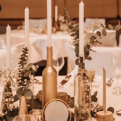 Centro de mesa con velas, eucalipto y detalles dorados