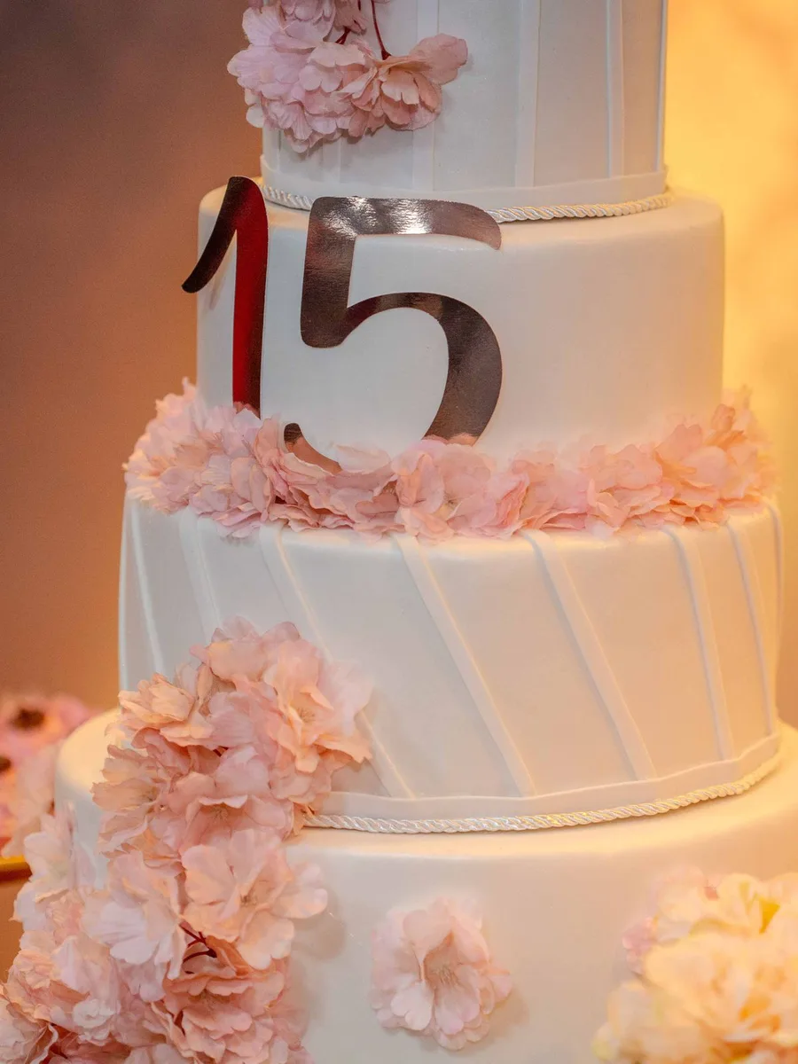 Pastel de quince años decorado con flores rosas y el número 15